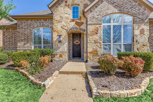 view of exterior entry featuring brick siding and stone siding