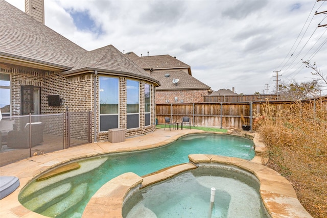 view of pool featuring a patio area, fence, and a pool with connected hot tub