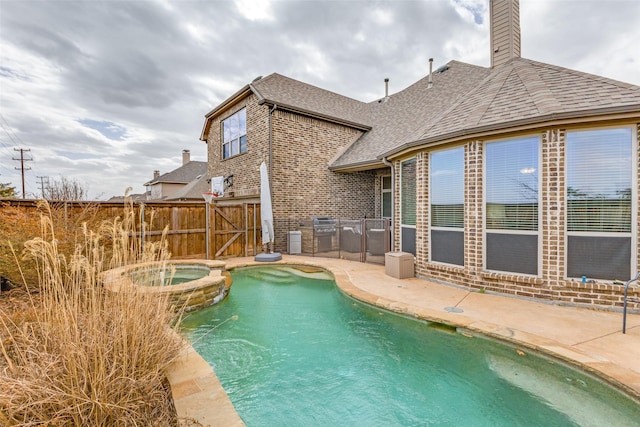 view of swimming pool with grilling area, a patio, a pool with connected hot tub, and fence