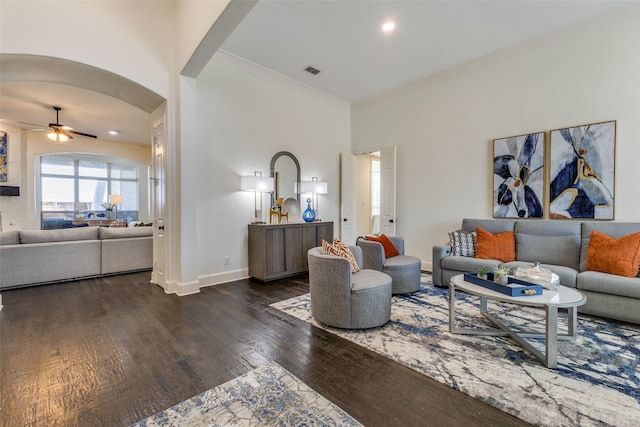 living area with visible vents, ceiling fan, ornamental molding, wood finished floors, and arched walkways