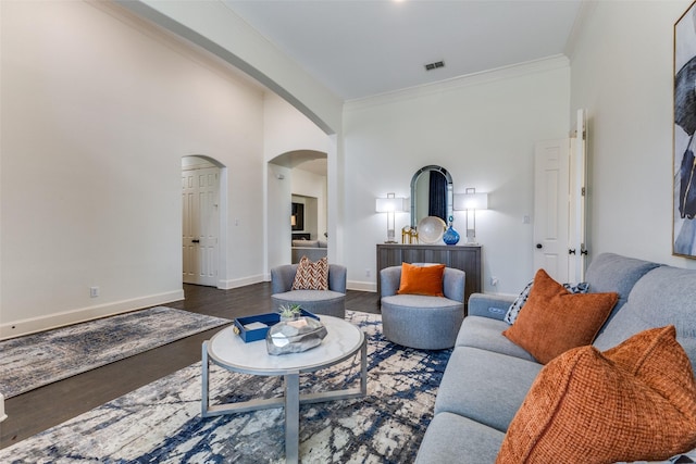 living area with visible vents, ornamental molding, wood finished floors, arched walkways, and baseboards