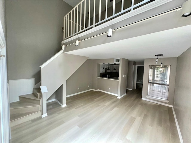 unfurnished living room with visible vents, stairs, baseboards, and wood finished floors