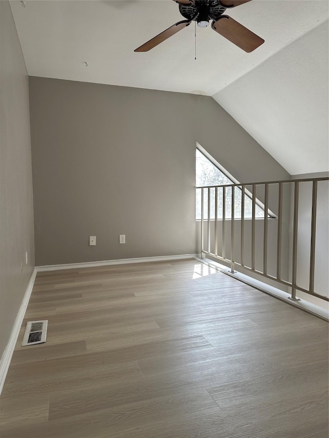 additional living space featuring visible vents, baseboards, vaulted ceiling, wood finished floors, and a ceiling fan