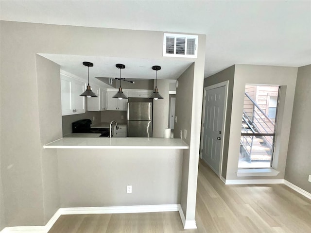 kitchen with visible vents, a healthy amount of sunlight, a peninsula, and freestanding refrigerator