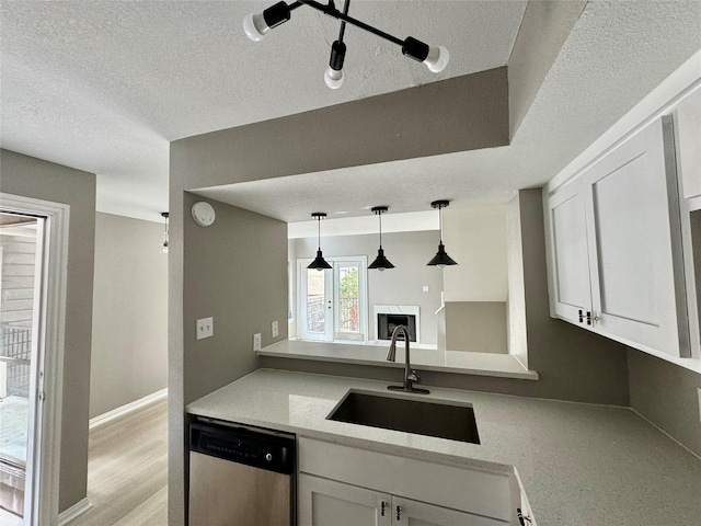 kitchen with a sink, a textured ceiling, dishwasher, and white cabinetry