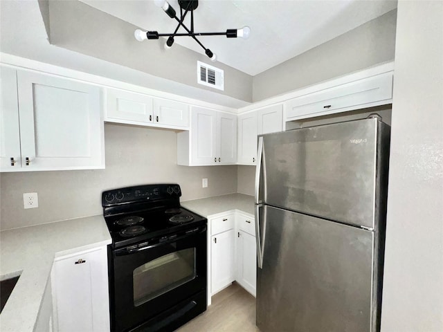 kitchen with electric range, white cabinetry, visible vents, and freestanding refrigerator