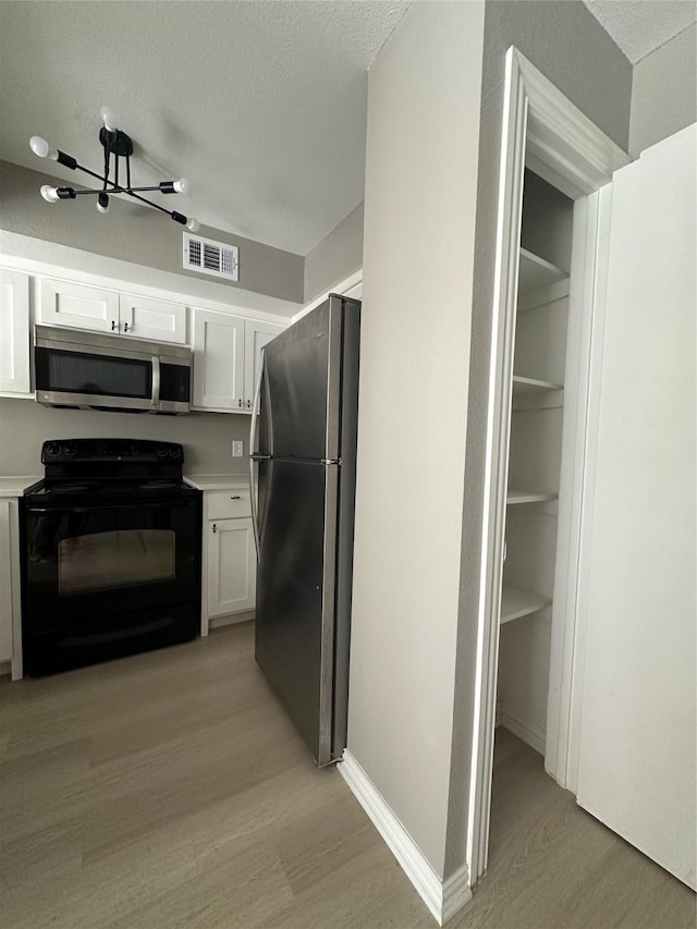 kitchen with visible vents, white cabinets, stainless steel appliances, and light wood-style flooring