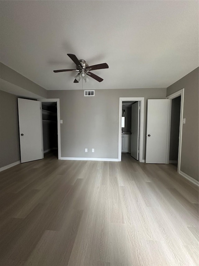 unfurnished bedroom featuring a ceiling fan, baseboards, visible vents, and light wood finished floors