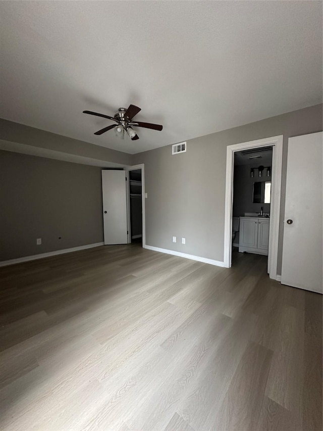 empty room with a sink, baseboards, wood finished floors, and ceiling fan