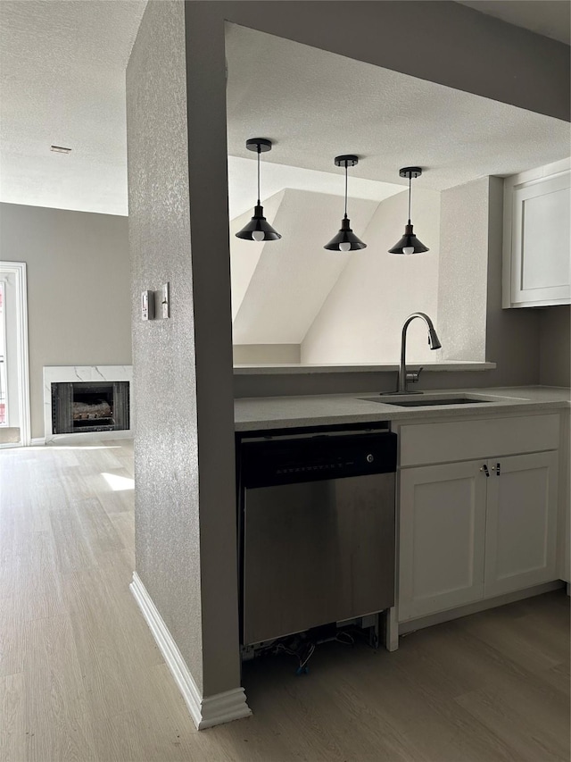 kitchen featuring dishwasher, white cabinetry, a textured ceiling, and a sink