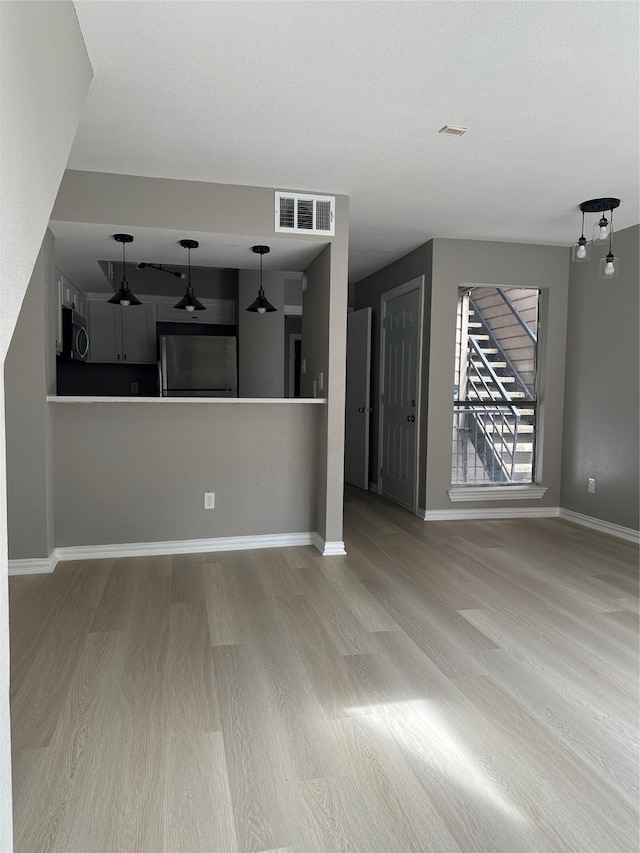 unfurnished living room with visible vents, baseboards, and wood finished floors