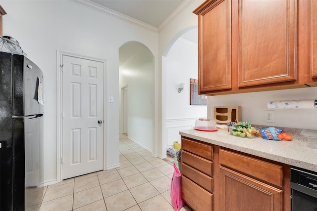 kitchen featuring light tile patterned floors, arched walkways, black appliances, crown molding, and brown cabinets