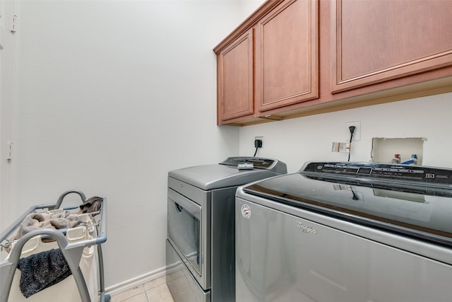 clothes washing area with light tile patterned floors, baseboards, cabinet space, and washer and clothes dryer