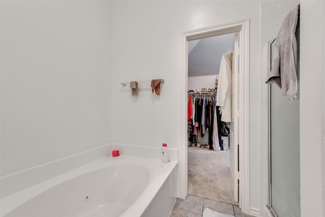 bathroom featuring a garden tub, a spacious closet, and a stall shower