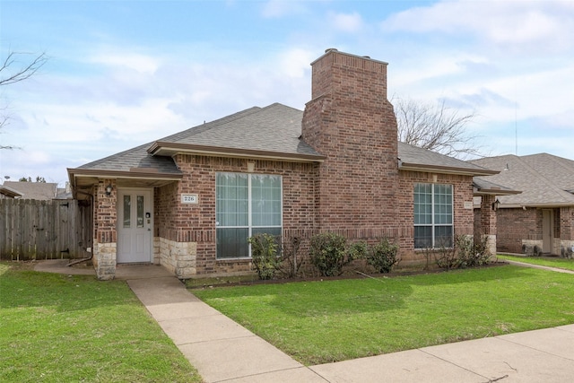 view of front of house featuring a front yard, brick siding, a chimney, and a shingled roof