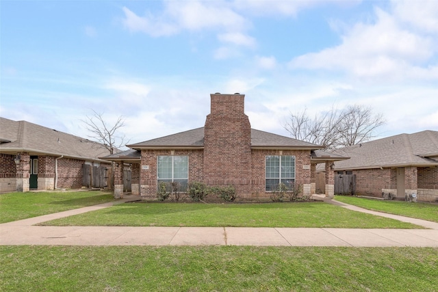 view of front of property with a front yard, fence, a chimney, a shingled roof, and brick siding