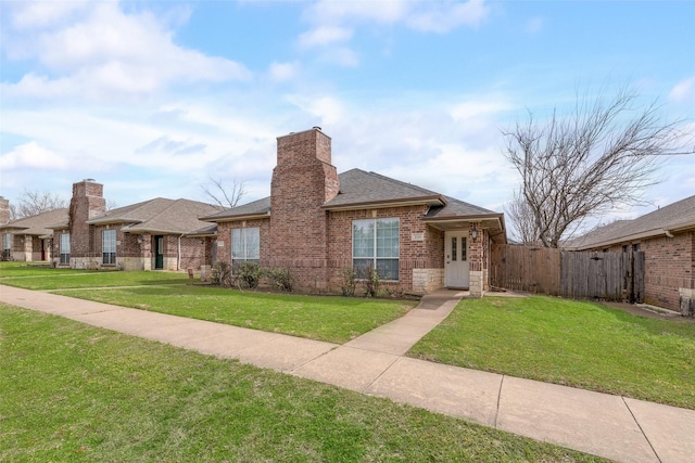 view of front of property with brick siding, a shingled roof, fence, a front yard, and a chimney