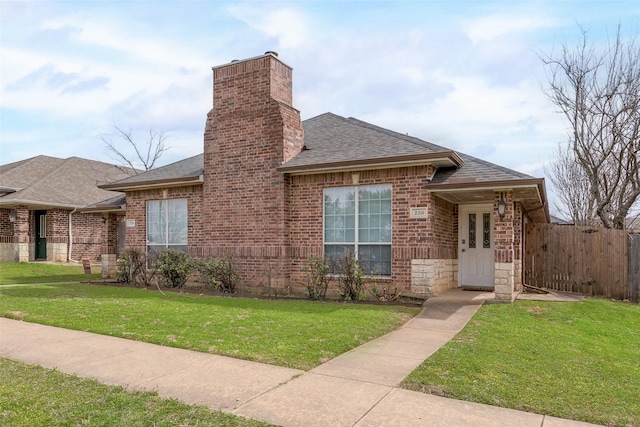 view of front of house with a chimney, a shingled roof, a front lawn, and brick siding