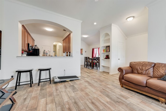 living room with light wood-style flooring, arched walkways, and ornamental molding