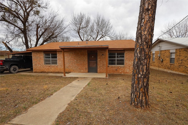 view of front facade featuring an attached carport, brick siding, roof with shingles, and a front lawn