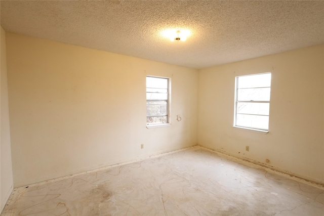 unfurnished room featuring a healthy amount of sunlight and a textured ceiling