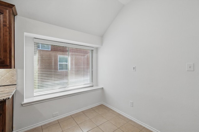 interior space with light tile patterned floors, baseboards, and lofted ceiling