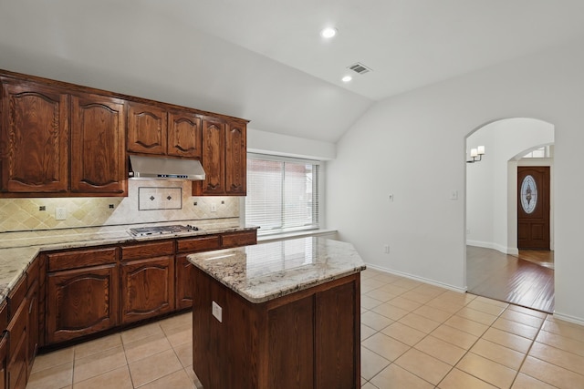 kitchen featuring visible vents, under cabinet range hood, vaulted ceiling, stainless steel gas stovetop, and light tile patterned flooring