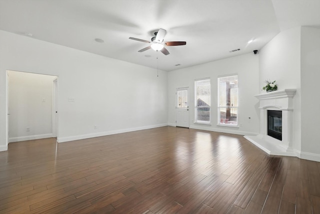 unfurnished living room with visible vents, baseboards, ceiling fan, a glass covered fireplace, and dark wood-style flooring