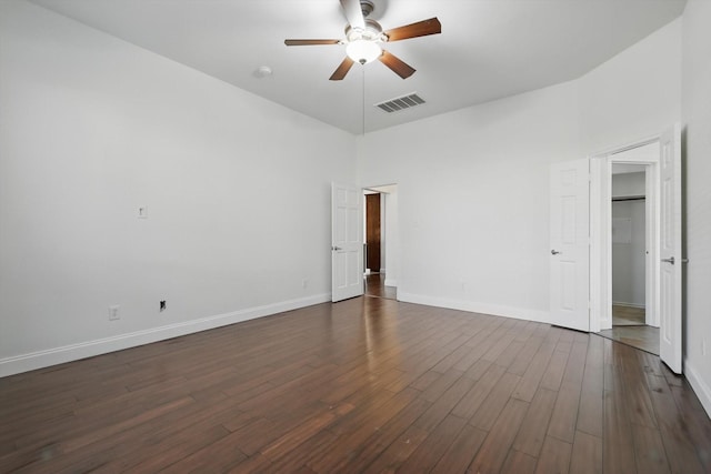 spare room with ceiling fan, visible vents, baseboards, and dark wood-style floors