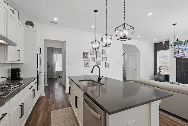 kitchen with dark countertops, appliances with stainless steel finishes, a chandelier, and a sink