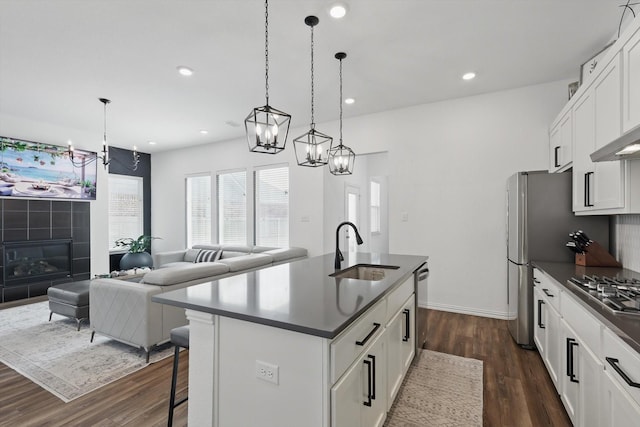 kitchen with a center island with sink, dark wood finished floors, an inviting chandelier, a sink, and dark countertops