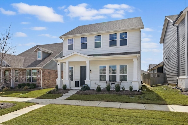 view of front of property featuring a front lawn and a shingled roof