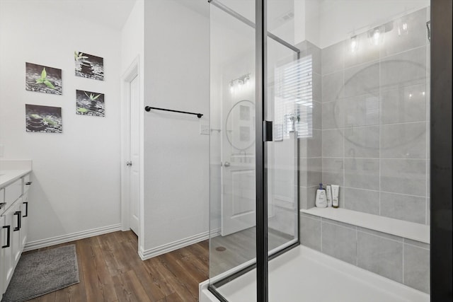 full bath featuring baseboards, wood finished floors, a stall shower, and vanity