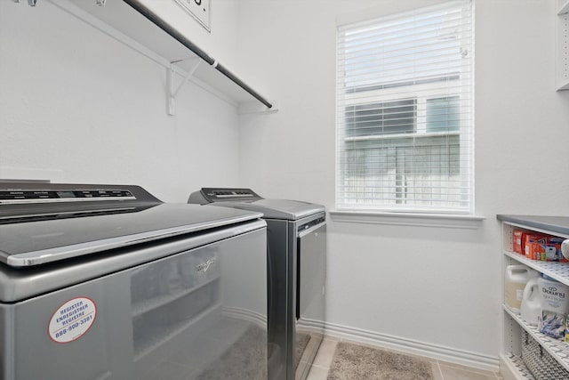 laundry area featuring light tile patterned flooring, laundry area, washing machine and dryer, and baseboards