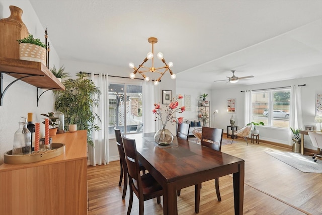 dining area with light wood-style flooring, ceiling fan with notable chandelier, and baseboards