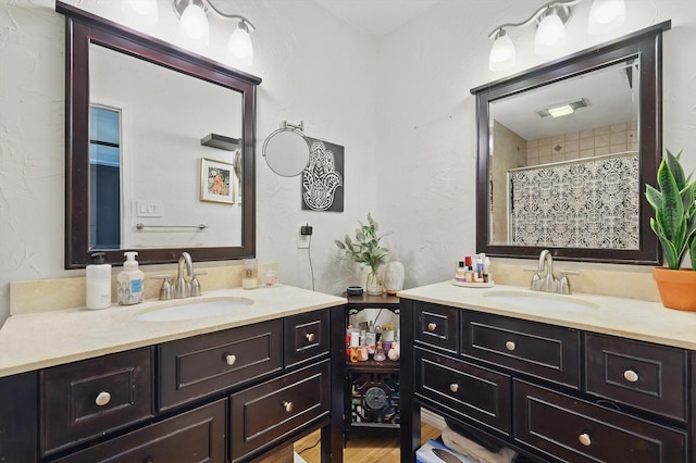 full bath featuring visible vents, curtained shower, two vanities, and a sink