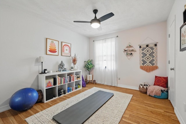 workout area featuring baseboards, ceiling fan, and wood finished floors