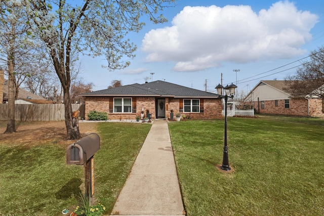 ranch-style home with a front lawn, fence, and brick siding