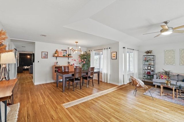 dining area featuring ceiling fan with notable chandelier, baseboards, and light wood-style floors