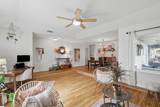 living area with visible vents, baseboards, light wood-style flooring, and a ceiling fan