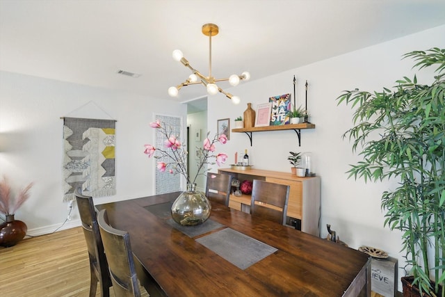 dining room with an inviting chandelier, wood finished floors, visible vents, and baseboards