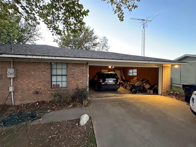 view of side of property with brick siding, an attached garage, concrete driveway, and a shingled roof