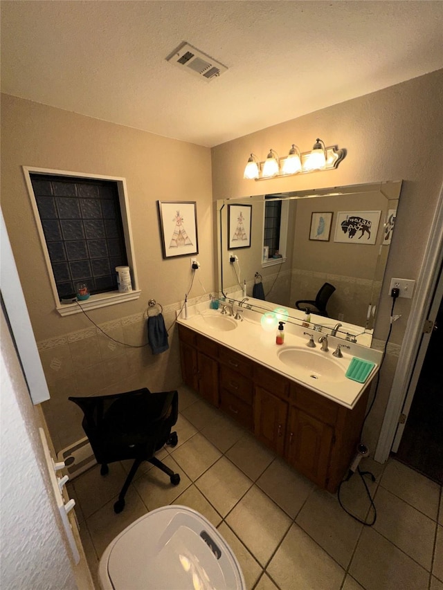 bathroom with tile patterned flooring, visible vents, double vanity, and a sink