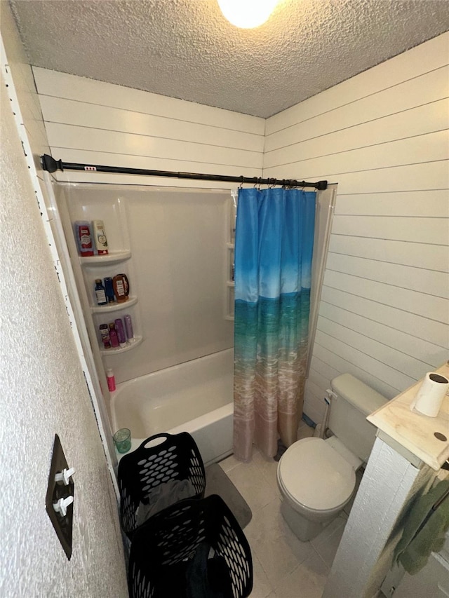 bathroom featuring wooden walls, tile patterned flooring, shower / bath combination with curtain, a textured ceiling, and toilet