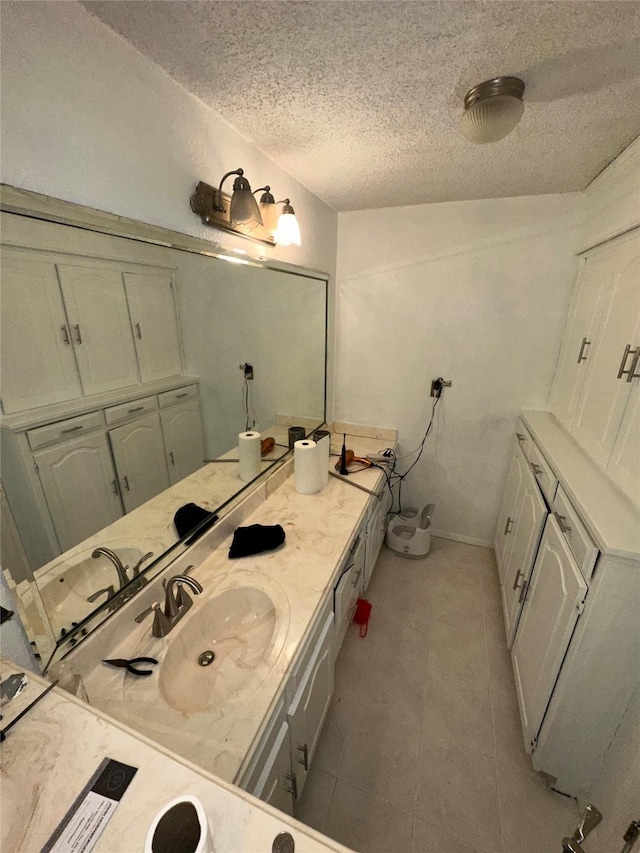 bathroom with tile patterned flooring, vanity, and a textured ceiling