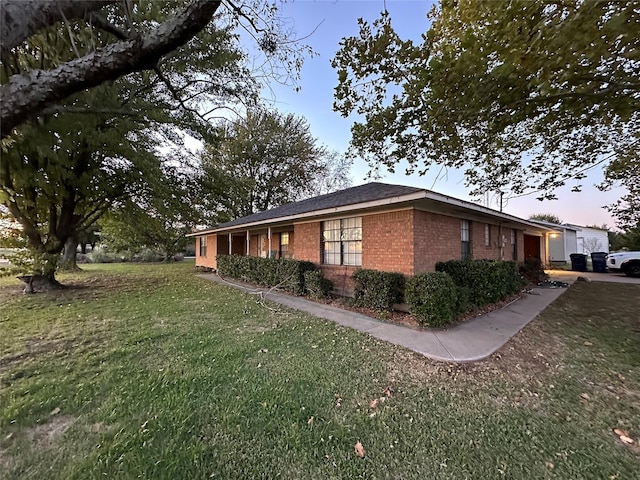 view of side of home featuring brick siding and a lawn