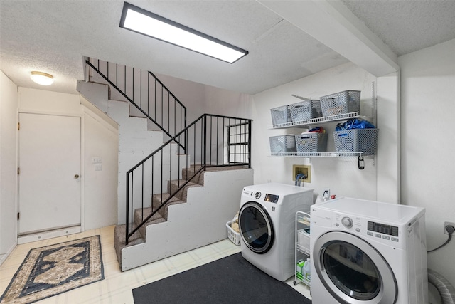 laundry room featuring washer and dryer, a textured ceiling, and tile patterned floors