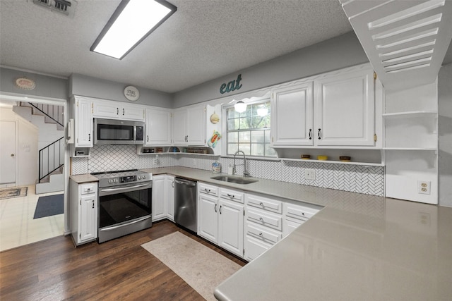 kitchen featuring visible vents, a sink, appliances with stainless steel finishes, white cabinets, and open shelves