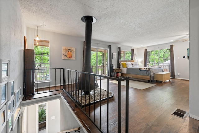 interior space with a wealth of natural light, visible vents, wood-type flooring, and a wood stove