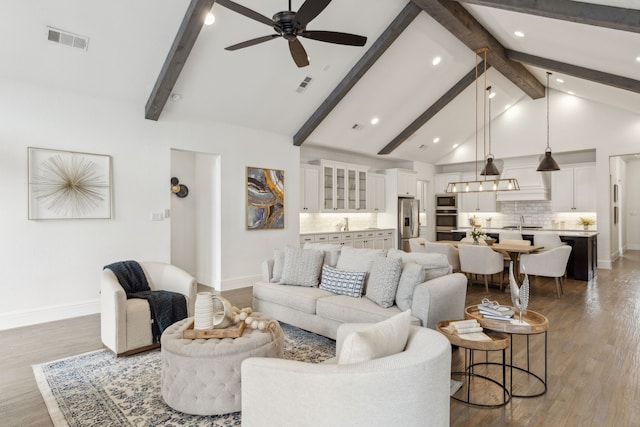 living room featuring visible vents, baseboards, ceiling fan, wood finished floors, and high vaulted ceiling